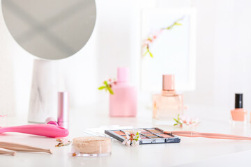 Beautiful blooming branches and cosmetics on light table in room