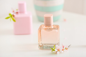 Perfume and fruit tree flowers on light table in room