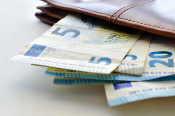 5 Euro banknotes and 20 Euro banknotes in a wallet. 