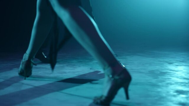 Closeup dancers legs dancing indoors. Partners feet doing latin dance steps.