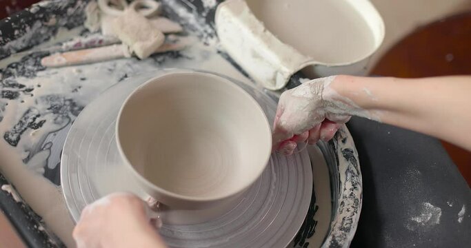 Female potter cut off a clay pot with string from a potter's wheel. Close-up shot, slow motion