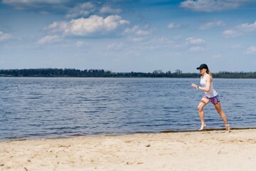 A beautiful blonde sporty woman runing on the shore of a lake in sportswear.