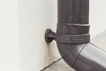 Pipe clamp with gutter system polymer pipe fastened on wall outdoors