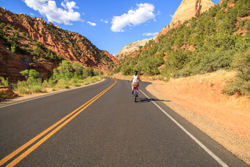 Woman riding a bike on a road through the desert