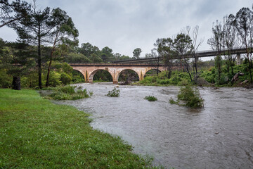 Fototapeta na wymiar Historic railway bridge over flooded Bargo River