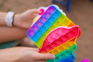 Colorful antistress sensory toy fidget push pop it in toddler's hands. Antistress trendy pop it...