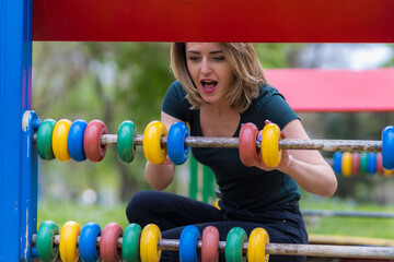 Young woman at the playground with toy educational abacus. Background