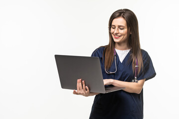 Young female doctor with laptop on grey background
