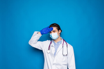 Frustrated doctor man in white wear over blue wall background. Doc is tired, bored of work, he...