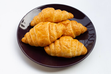Tasty croissants in plate on white background.