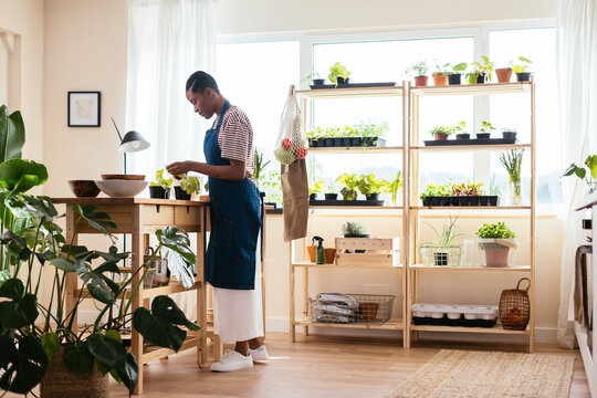Black female tending plants at home