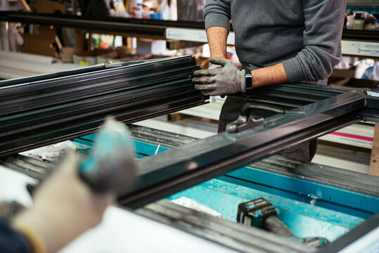 Unrecognizable worker assembling window frame