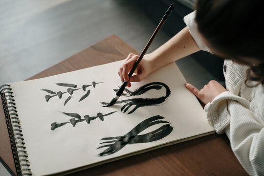 Young woman writing japanese kanji characters with a brush and ink