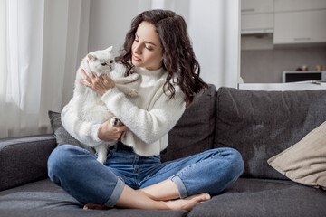 Pretty young woman playing with her cat and looking peaceful