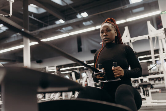 Strong sportswoman doing exercise on rowing machine