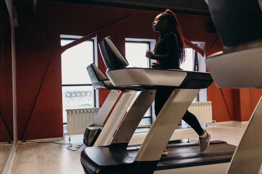 Determined black woman running on treadmill in gym