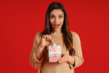 Attractive young woman in casual clothing holding a present and smiling