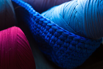 Two skeins of yarn in knitted with hook basket. Blu, indigo and burgundy threads. knitted fabric....