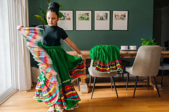 Tween girl trying on her traditional Mexican folkloric skirt at home