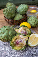 Fresh ripe green artichokes heads with yellow lemons ready to cook