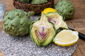 Fresh ripe green artichokes heads with yellow lemons ready to cook