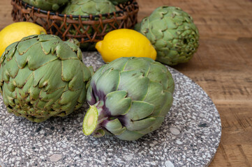 Fresh ripe green artichokes heads with yellow lemons ready to cook