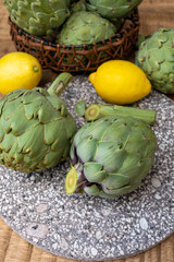 Obraz premium Fresh ripe green artichokes heads with yellow lemons ready to cook