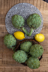 Fresh ripe green artichokes heads with yellow lemons ready to cook