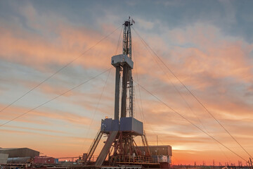 A site in the northern tundra at an oil and gas field. Drilling rig for drilling wells. Infrastructure and drilling equipment for drilling operations. Beautiful expressive sky