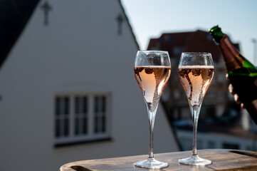 Drinking of rose champagne sparkling wine from flute glasses on outdoor terrace in France