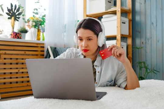Serious woman with credit card working on laptop at home