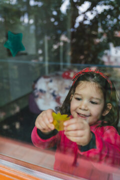 Little Girl Putting a Sticker on the Window