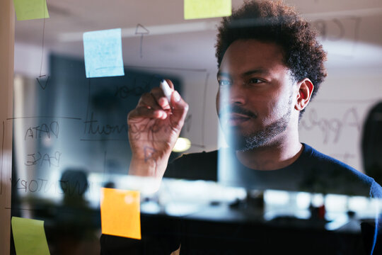 Black man writing on glass wall