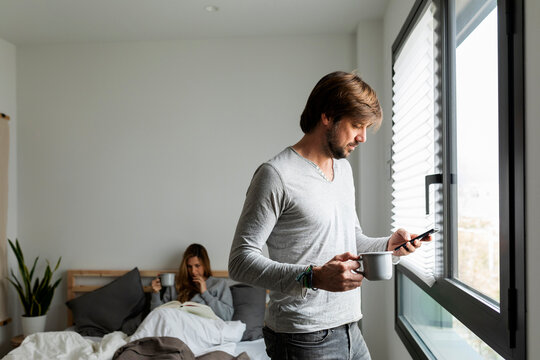 man standing in bedroom Using smartphone 