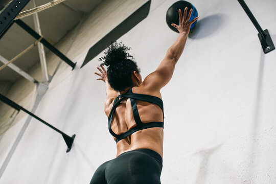 Unrecognizable sportswoman throwing ball into wall 