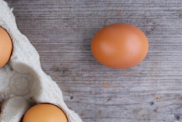 Organic brown egg on wooden table near the box. Healthy food concept.