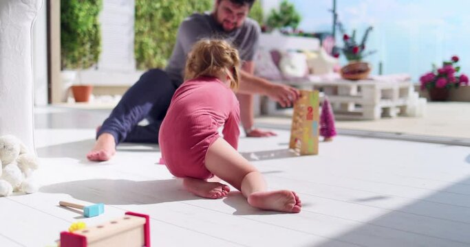 baby girl crawling on the floor at sunny living room with patio, having fun and playing with father at home, family games