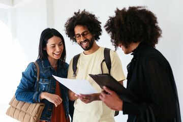 Happy diverse couple examining apartment scheme with realtor