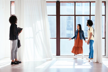 Excited diverse couple examining apartment with realtor