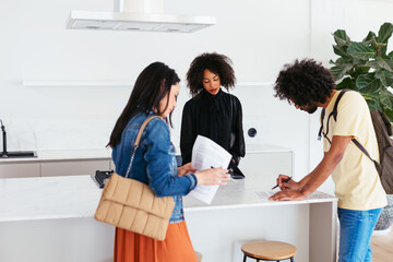 Diverse couple reading and signing contract with real estate agent