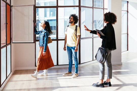 Multiracial couple examining windows with real estate agent