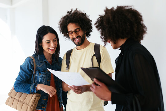 Happy diverse couple examining apartment scheme with realtor