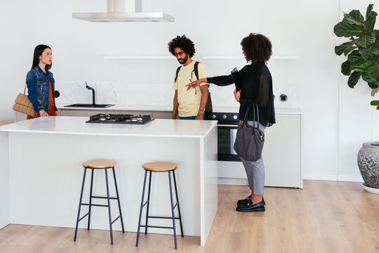 Black realtor showing kitchen to diverse couple