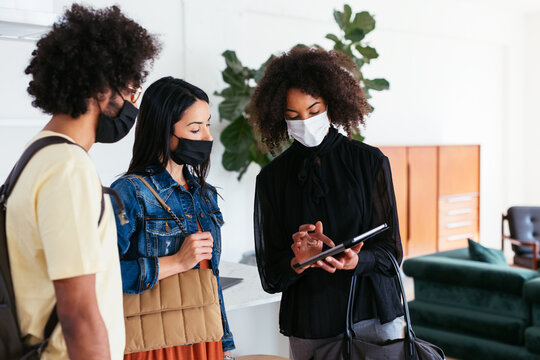 Multiracial couple and realtor using tablet in new flat during pandemic
