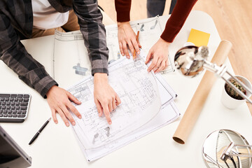 Colleagues with blueprint discussing project in office