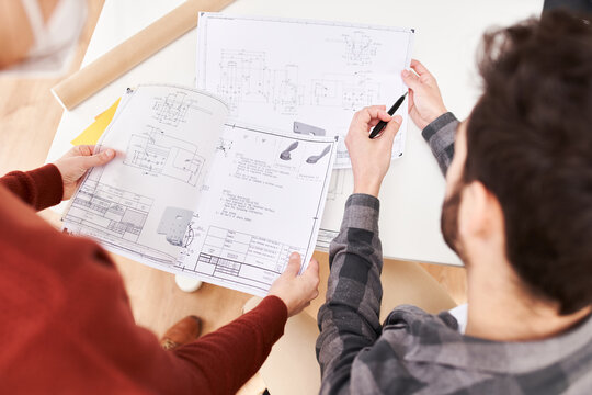 Technicians analyzing blueprints at workplace