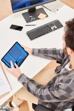 Male designer comparing 3D models on tablet and computer