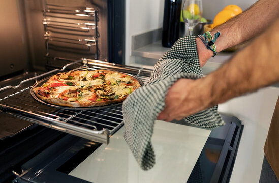 man taking pizza out of the oven