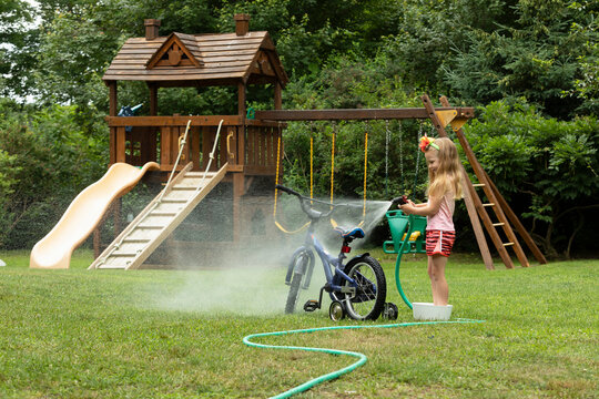 Young girl Washing her bicycle in the backyard of home 