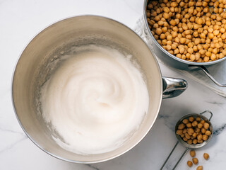 Whipped aquafaba in planetary mixer bowl, vertical. Chickpea water brine aquafaba whipped. Egg replacement in coocking. Vegan concept. Top view or flat lay. Copy space